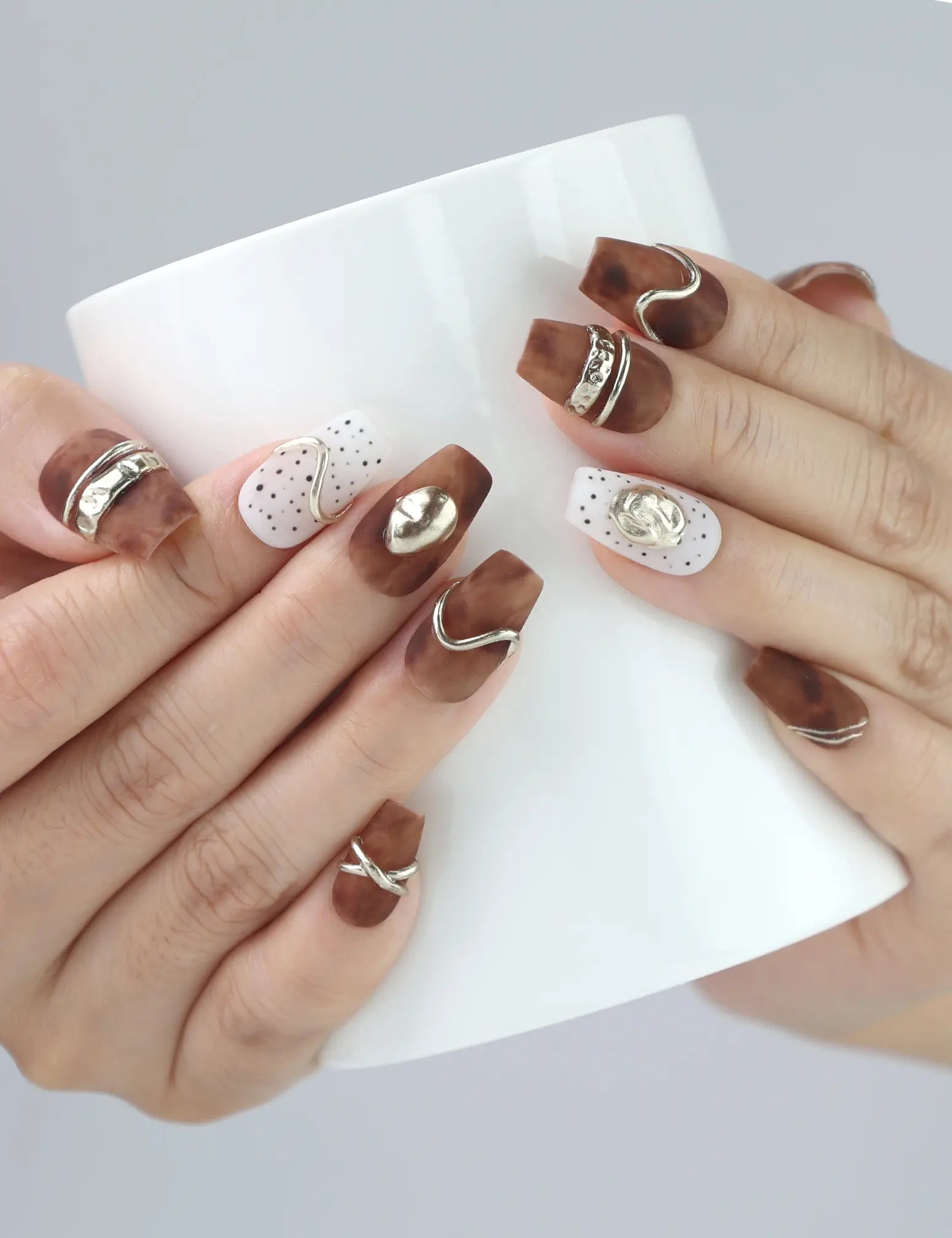 Woman holding a ceramic mug while wearing Naillover Caramel Luxe press on nails, showcasing refined office-ready style.