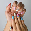 Close-up of handmade nails with multicolor graphics, fun icons, and cheerful pop-style designs