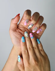 Close-up of handmade nails with multicolor graphics, fun icons, and cheerful pop-style designs