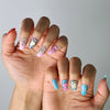 Vibrant and quirky short nails with glossy finish, featuring doodled stars, faces, and cartoon-inspired art