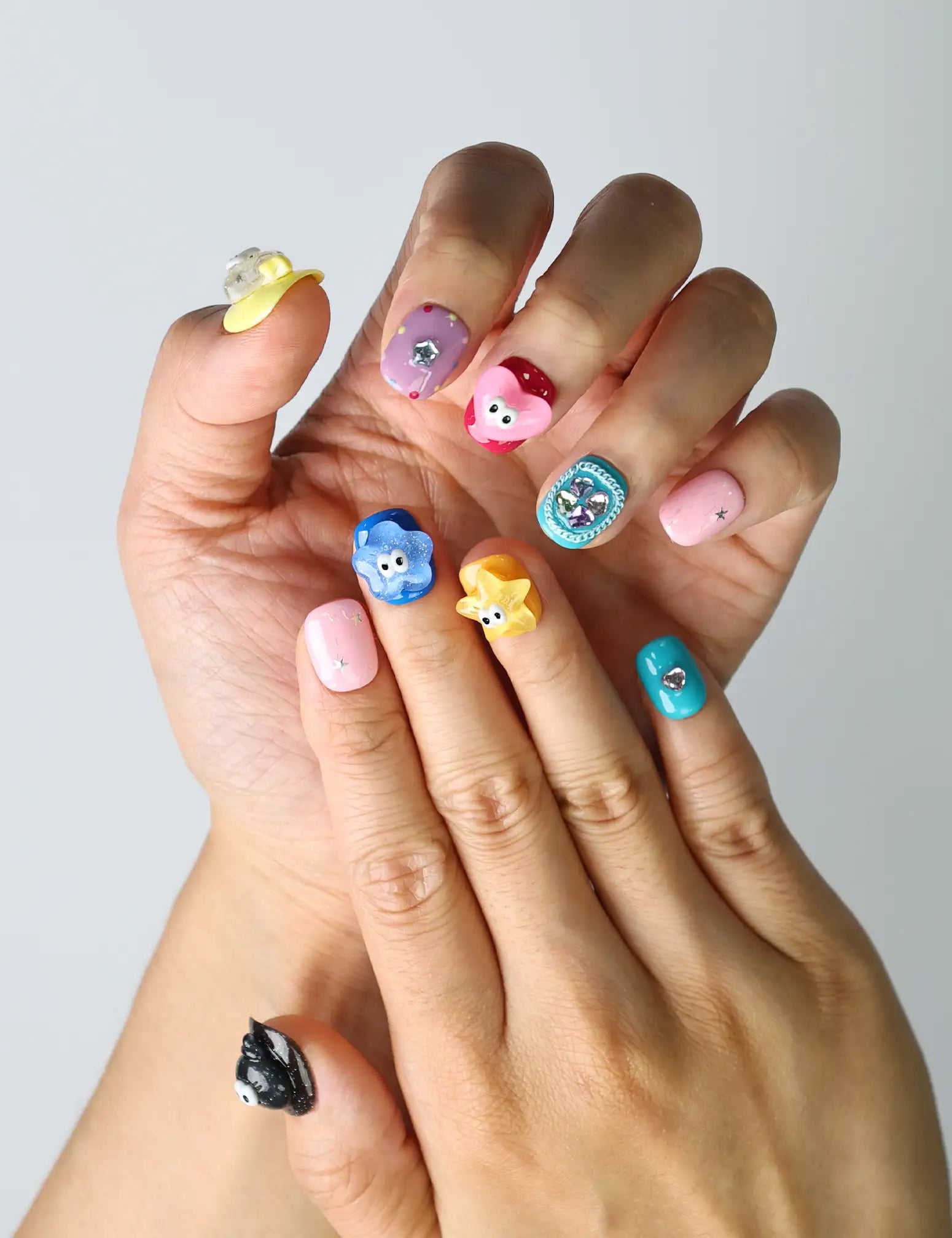 Close-up of quirky press-on nails featuring bright colors, raised floral accents, and fun cartoon-like eye details