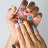 Close-up of quirky press-on nails featuring bright colors, raised floral accents, and fun cartoon-like eye details