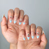 Side view of almond-shaped nails with playful fruit accents and checkered French tips in a fresh summer style