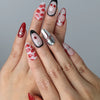 Hand model wearing medium almond red nails with 3D cherry lip art and cute pink bow accents
