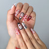 Close-up of glossy red press-on nails featuring bold lip motifs and girly ribbon designs