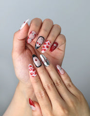 Close-up of glossy red press-on nails featuring bold lip motifs and girly ribbon designs