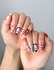 Side view of handmade almond nails with vibrant red color, pouty lip charms, and playful bow details