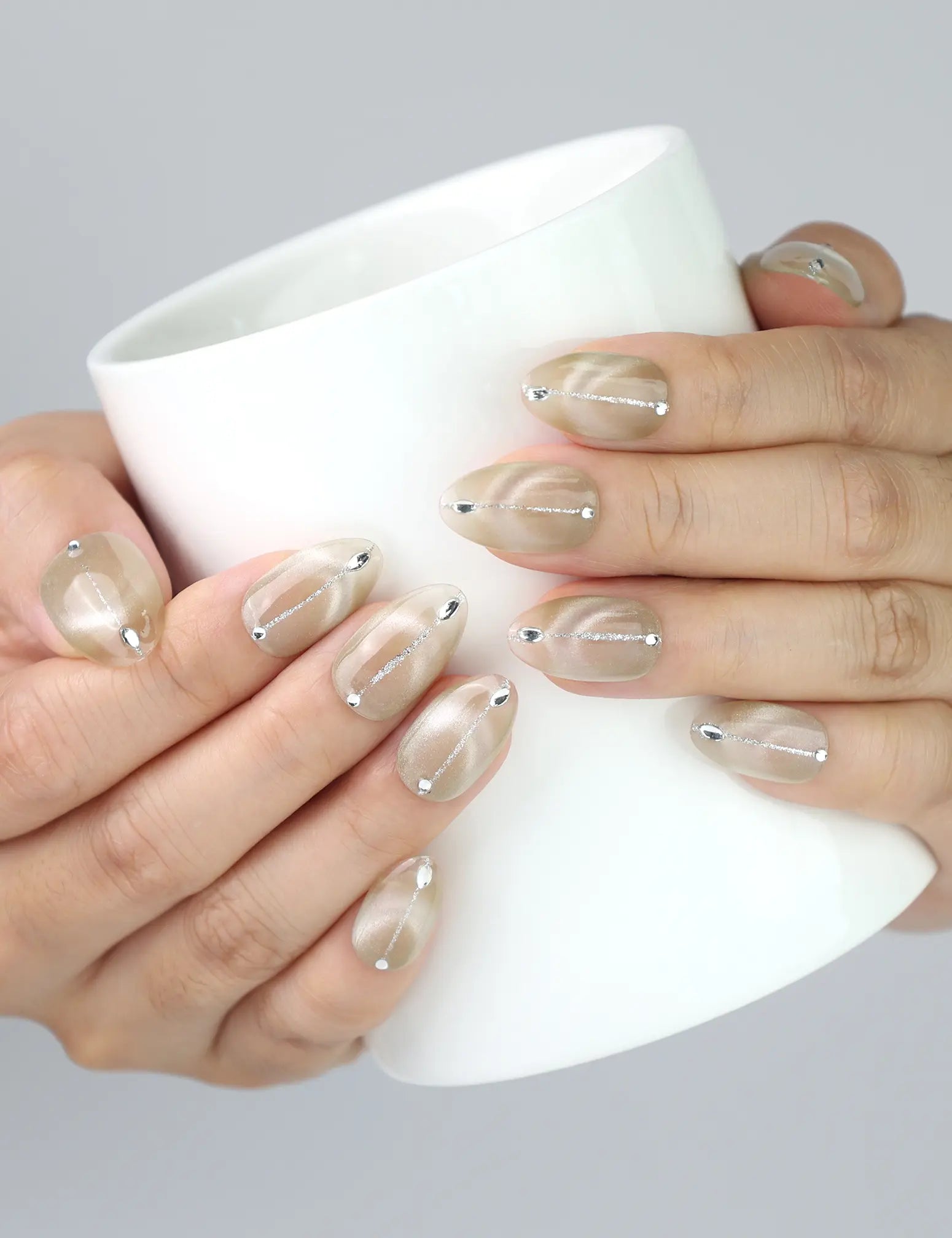 Naillover Clean Sand nails holding a ceramic mug, showcasing neutral tones and subtle nail art in daily use.