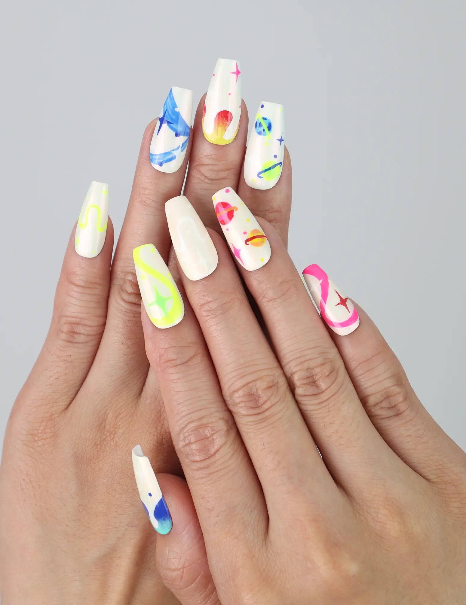 Hand showcasing coffin-shaped medium press on nails with neon squiggles, star accents, and vibrant abstract designs by Naillover
