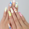 Hand showcasing coffin-shaped medium press on nails with neon squiggles, star accents, and vibrant abstract designs by Naillover