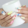 Holding a cup while wearing Naillover’s handmade coffin cute nails with multicolor abstract patterns and starry accents