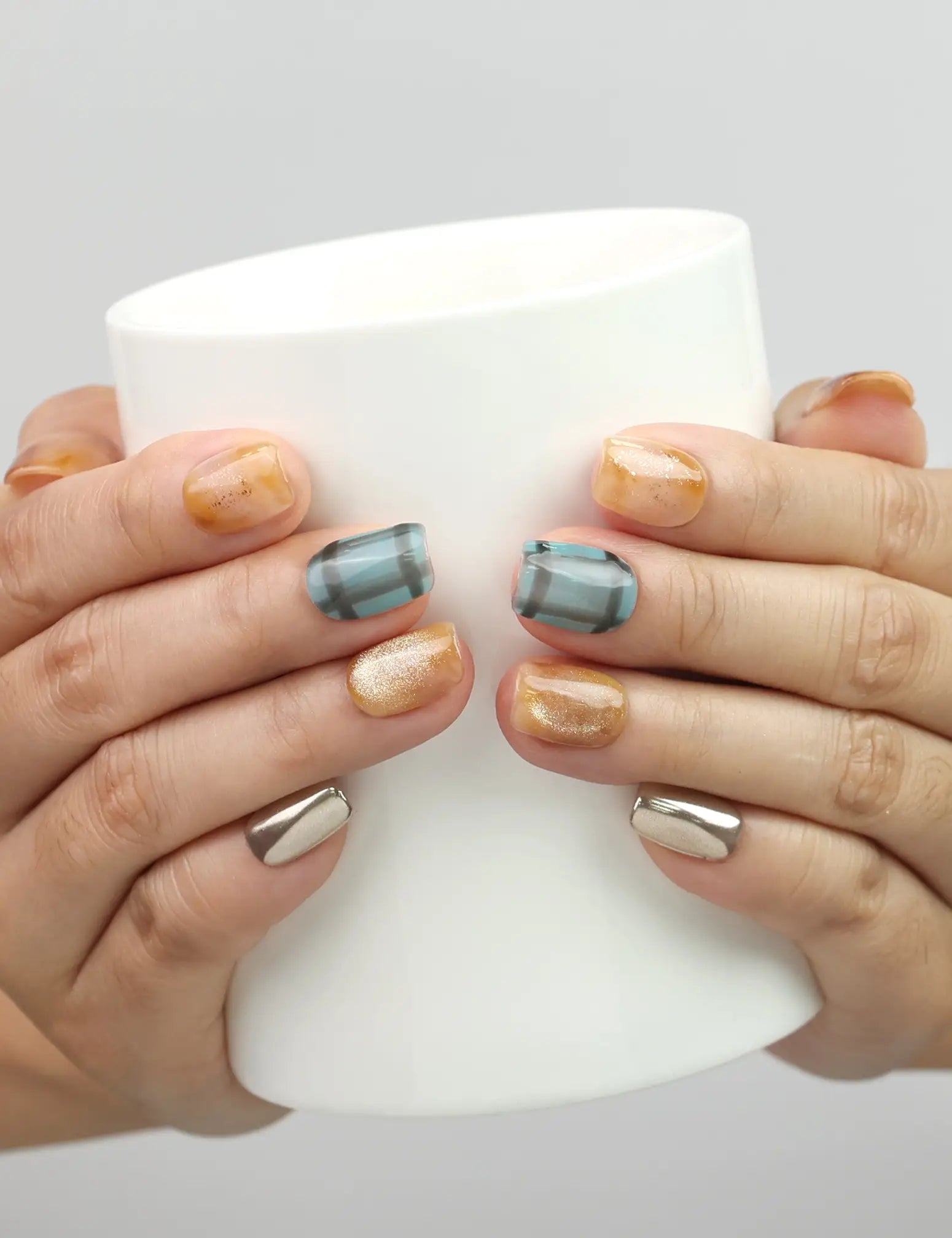 Hand holding a cup while wearing Naillover Cozy Plaid Glaze plaid short coffin press on nails with cat-eye shimmer, Singapore handmade nails