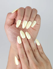 Close-up of handmade press-on nails in soft yellow tones with smooth almond shape and glossy finish