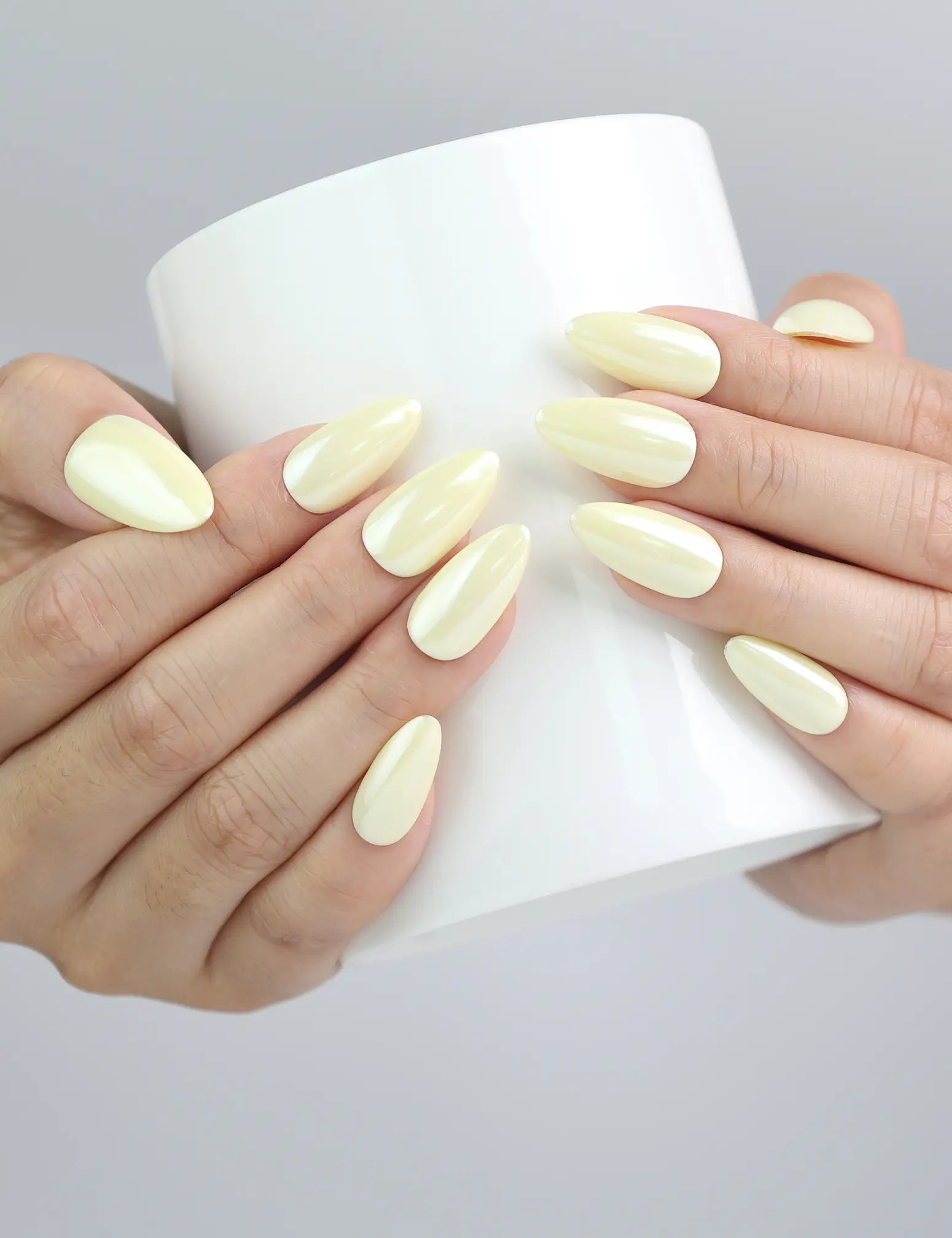 Hand holding a cup, featuring cheerful pastel yellow nails with a fresh and cozy aesthetic