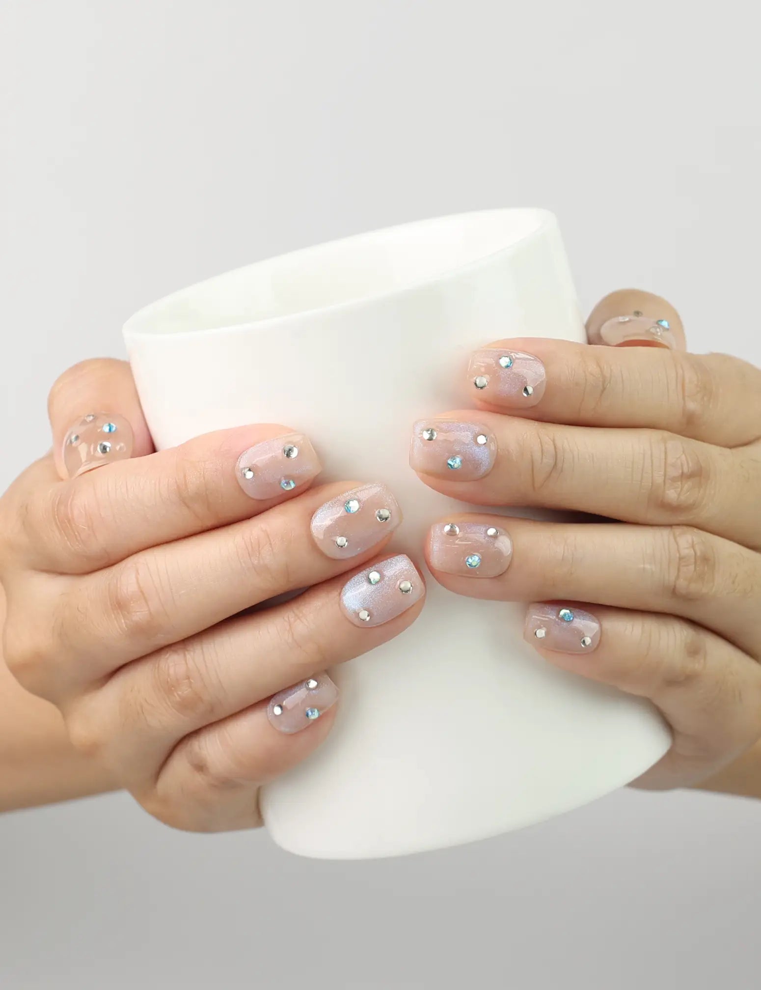 Crystal Dust nude short press on nails holding a white coffee cup, showcasing classic handmade nail design by naillover