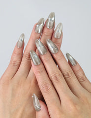 Hand gesture showing medium-length silver press on nails with metallic chrome shine and gem accents by Naillover