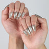 Close-up of hand wearing shiny silver press on nails with dimensional gem details for a futuristic look