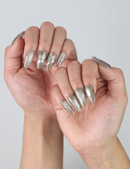 Close-up of hand wearing shiny silver press on nails with dimensional gem details for a futuristic look