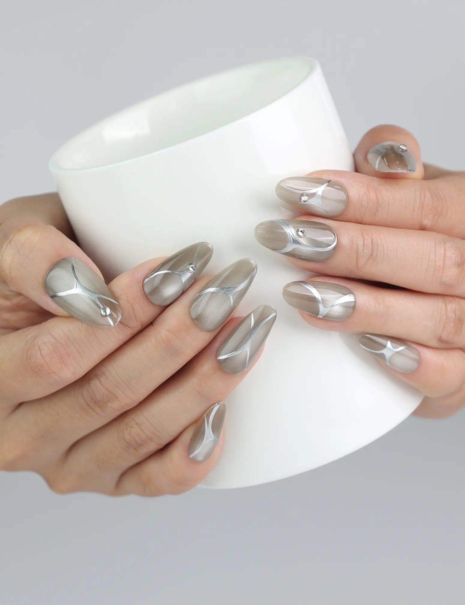 Hand holding a cup while flaunting metallic chrome medium press on nails with subtle gem sparkle by Naillover