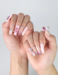 Side view of nude-to-pink gradient press-on nails in coffin shape with elegant marble effect and crystal charm detail