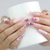 Hand holding a cup, showcasing Naillover’s pink coffin nails with glossy marble finish and statement silver gemstones