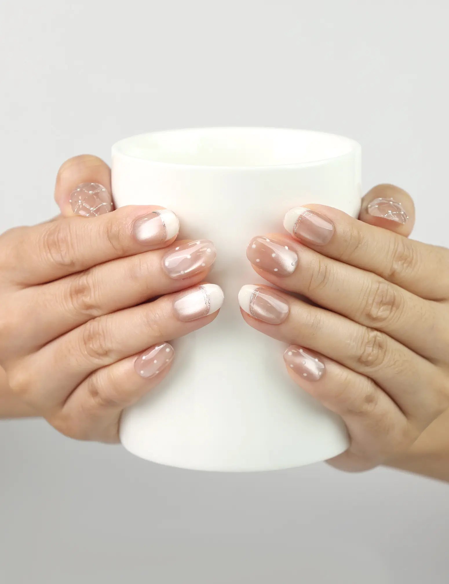 Model holding a coffee cup while wearing Dewdrop Delight nude shimmer handmade Singapore press on nails