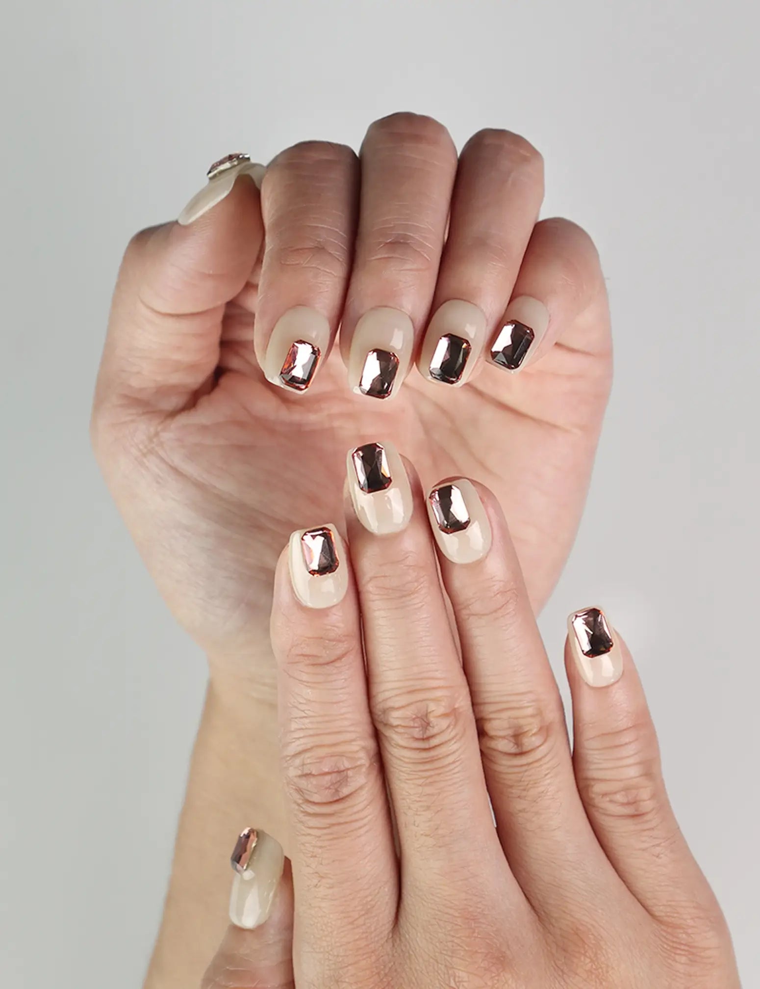Close-up of Dream Glitter Singapore press-on nails with pink rhinestones on beige base, cute nails by naillover