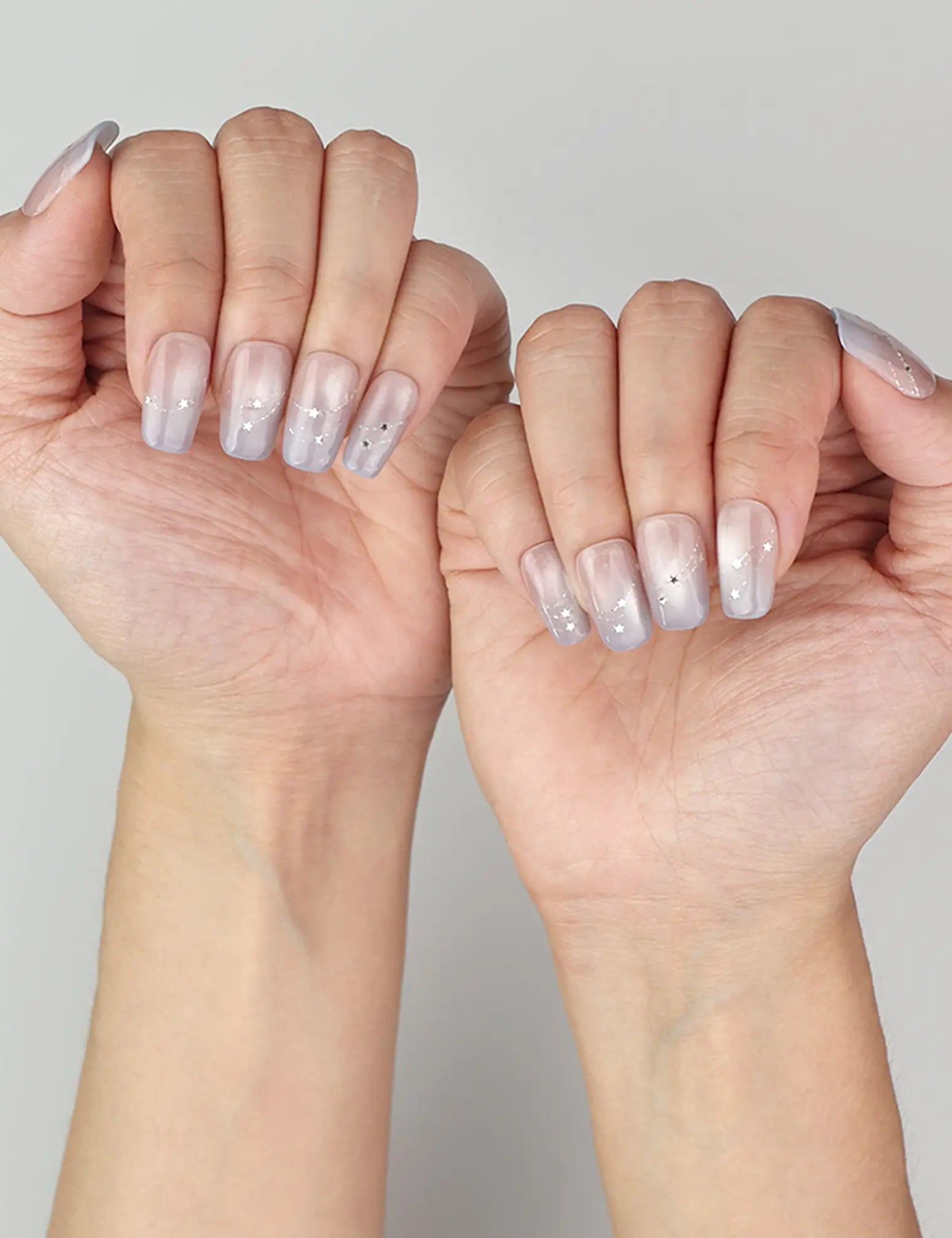 Eclipse Stars handmade press on nails SG styled on fingers, glowing under light with celestial cat eye effect