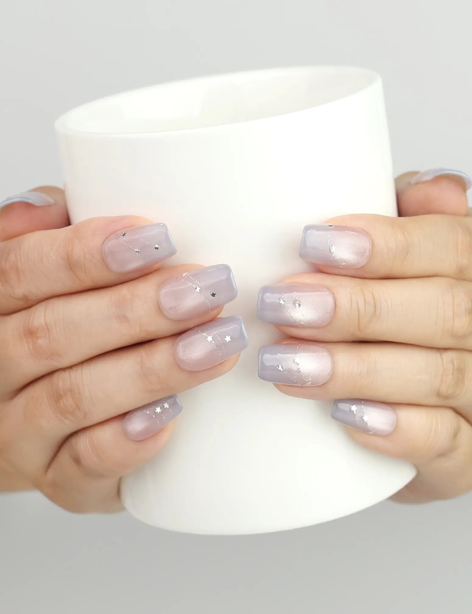 Eclipse Stars pastel cat eye nails by naillover holding a glass cup, showcasing salon-quality shine