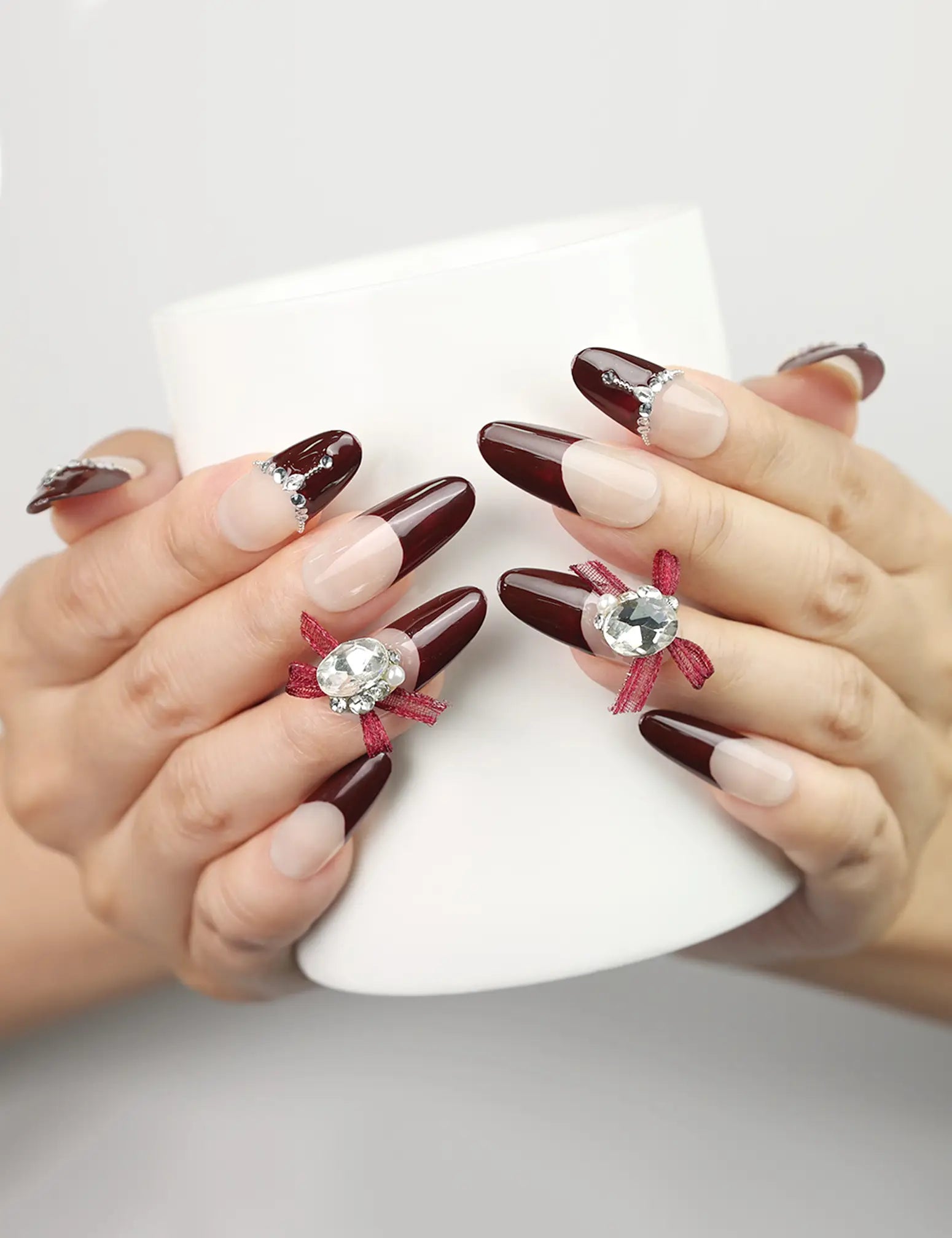 Hand holding a cup wearing Eternal burgundy press-on nails with silver accents, Singapore handmade nails by naillover