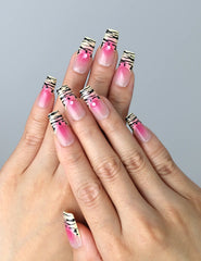 Hand model wearing pink press-on nails with soft ombré base and bold black zebra print details