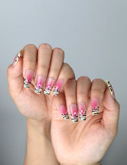 Side view of press-on nails with glossy pink-to-clear ombré and striking zebra patterns