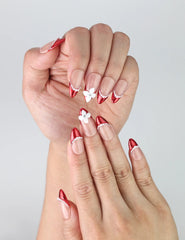 Close-up of Naillover’s handmade pink and red press-on nails with delicate 3D flower art and luminous pearls