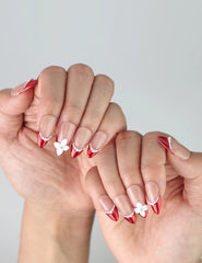 Side view of almond red nails with gradient pink base, showcasing handcrafted flowers and pearl accents