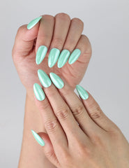 Close-up of handmade press-on nails in light green with a smooth almond silhouette and high-gloss finish