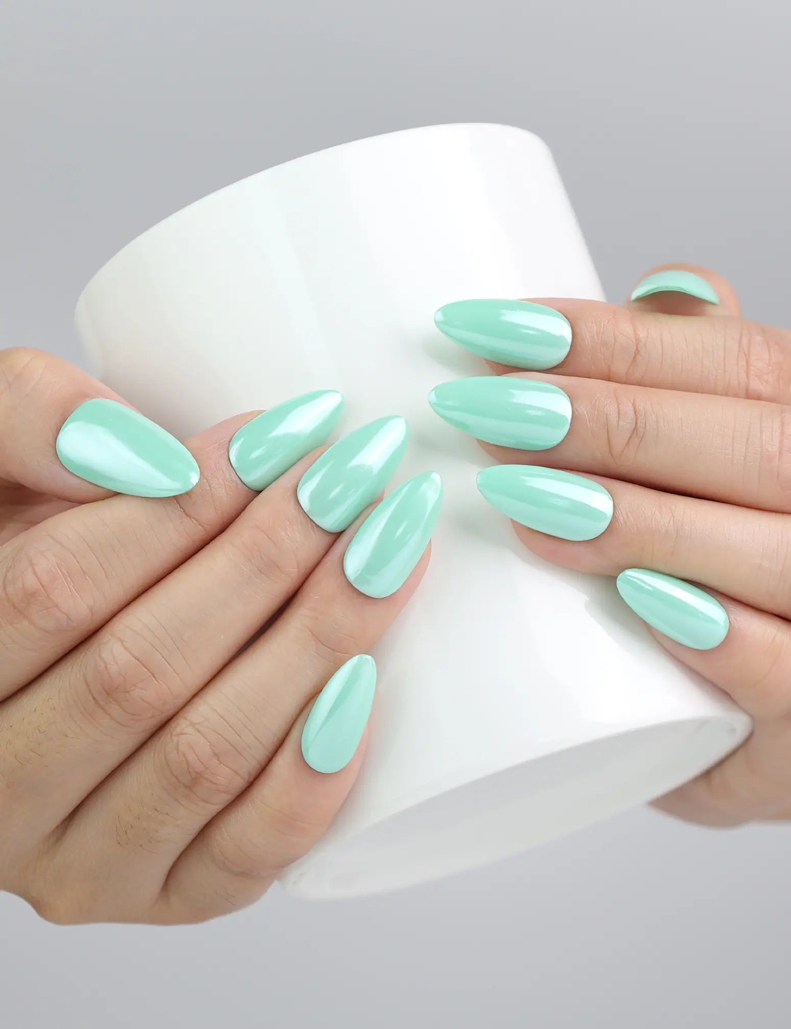 Hand holding a cup while wearing Naillover pastel green press-on nails with a serene spring aesthetic