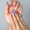Close-up of Naillover’s handmade nails featuring whimsical cherry prints, soft daisy blooms, and colorful flower patterns