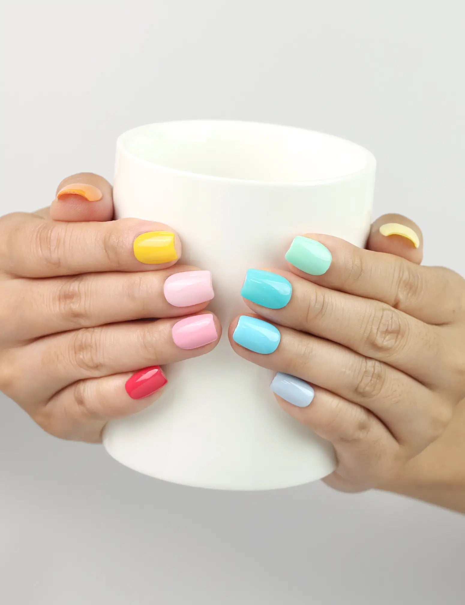 Woman holding a coffee cup wearing Fruit Punch Singapore press on nails by Naillover in juicy summer shades