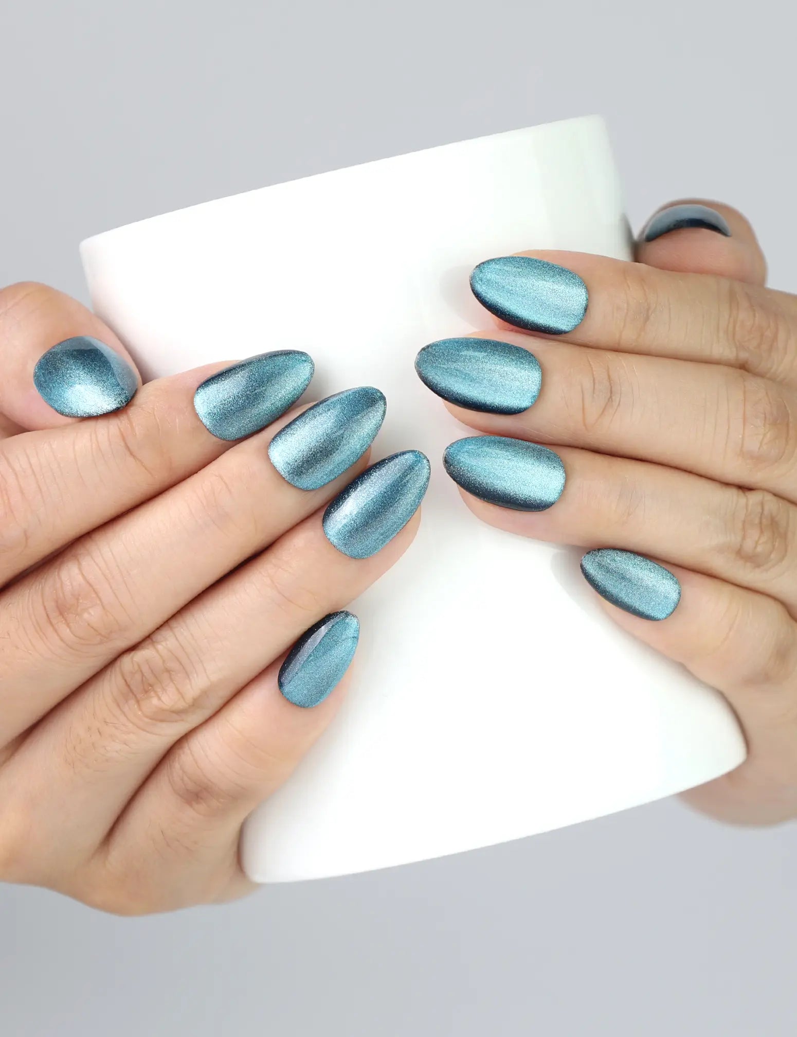 Hand holding a glass cup, showcasing Galaxy Gleam deep blue glitter press on nails by Naillover.