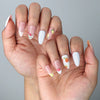 Side view of glossy almond nails with soft pink base, intricate flower art, and fruity accent designs