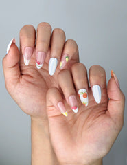 Side view of glossy almond nails with soft pink base, intricate flower art, and fruity accent designs
