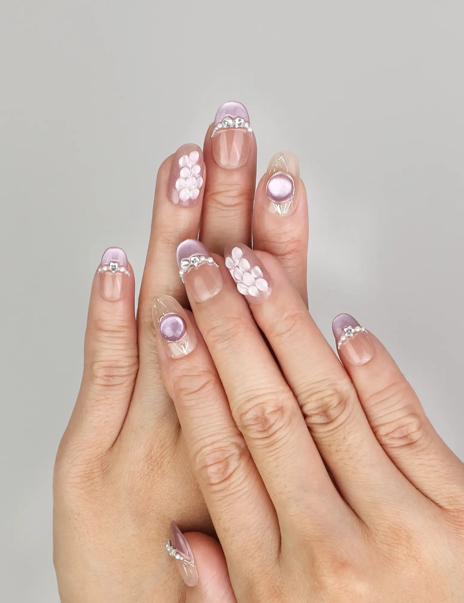 Hand wearing Naillover Gemstone Latte handmade press on nails with shimmering blue hues, seashell details, and pearl accents.