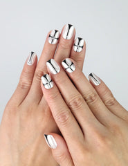 Hand model wearing short squoval press-on nails with nude base and sleek black chrome geometric nail art
