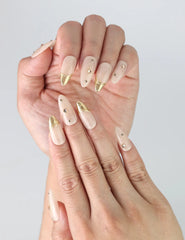 Close-up of Naillover’s handmade almond nails featuring nude polish and shimmering gold details