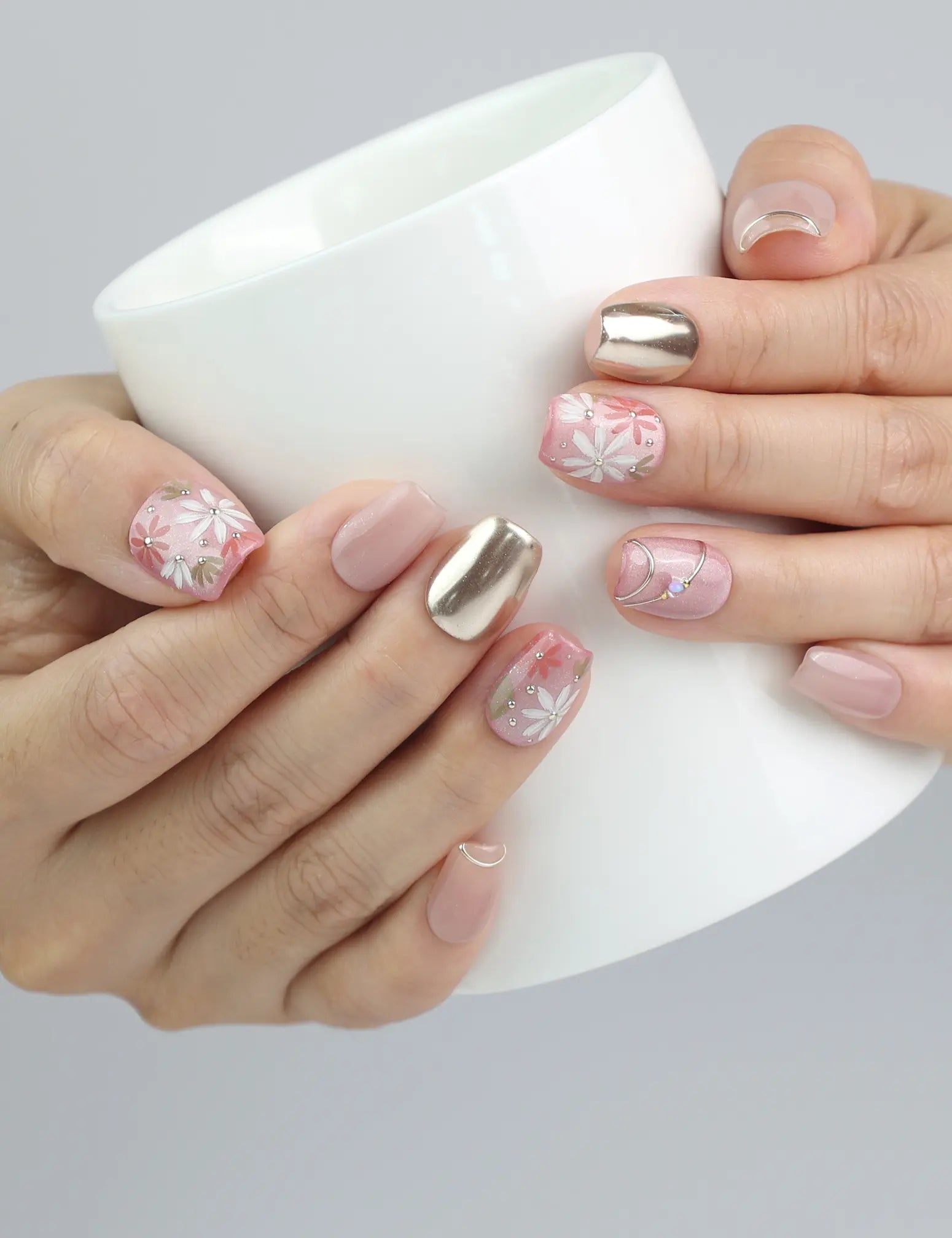 Hand holding a cup, showcasing Naillover’s red press-on nails with ornate floral designs and luxe gold touches