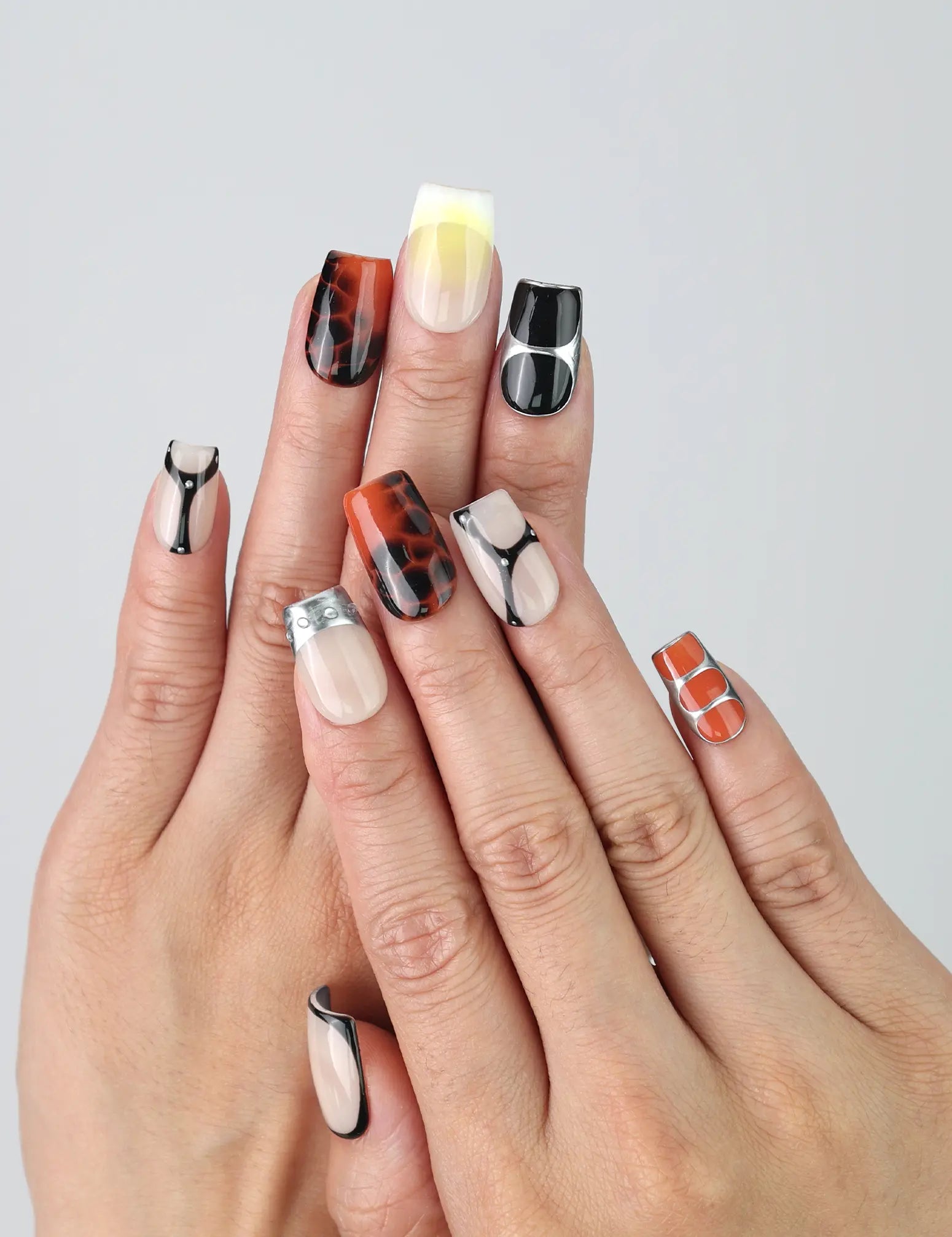 Hand gesture showing short square press on nails with glossy gold finish and caramel marble accents by Naillover