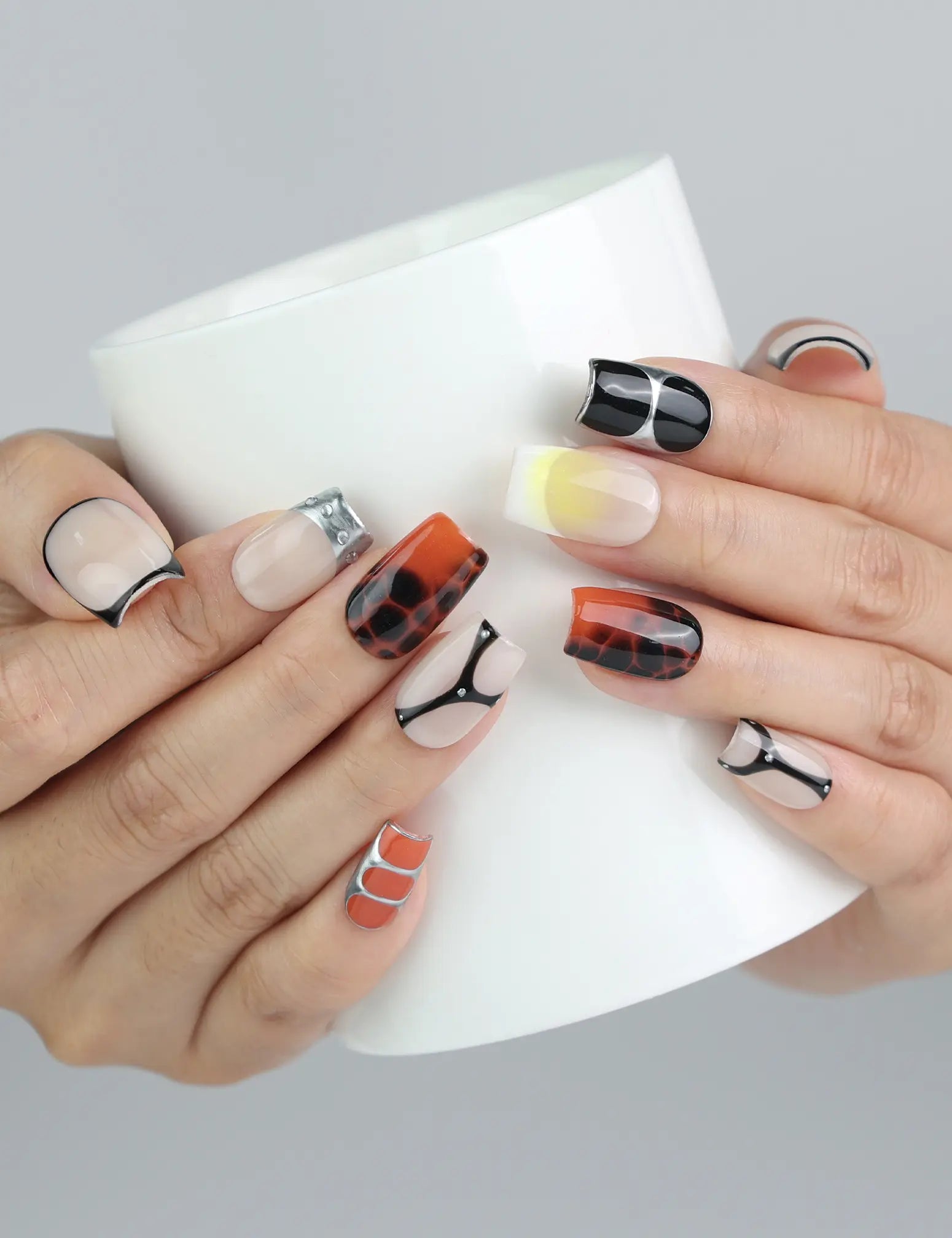 Hand holding a cup while wearing Singapore handmade gold and caramel marble short square press on nails by Naillover