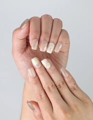Fingers displayed wearing Naillover’s short pale pink handmade nails featuring subtle gold detailing and a light-catching glow