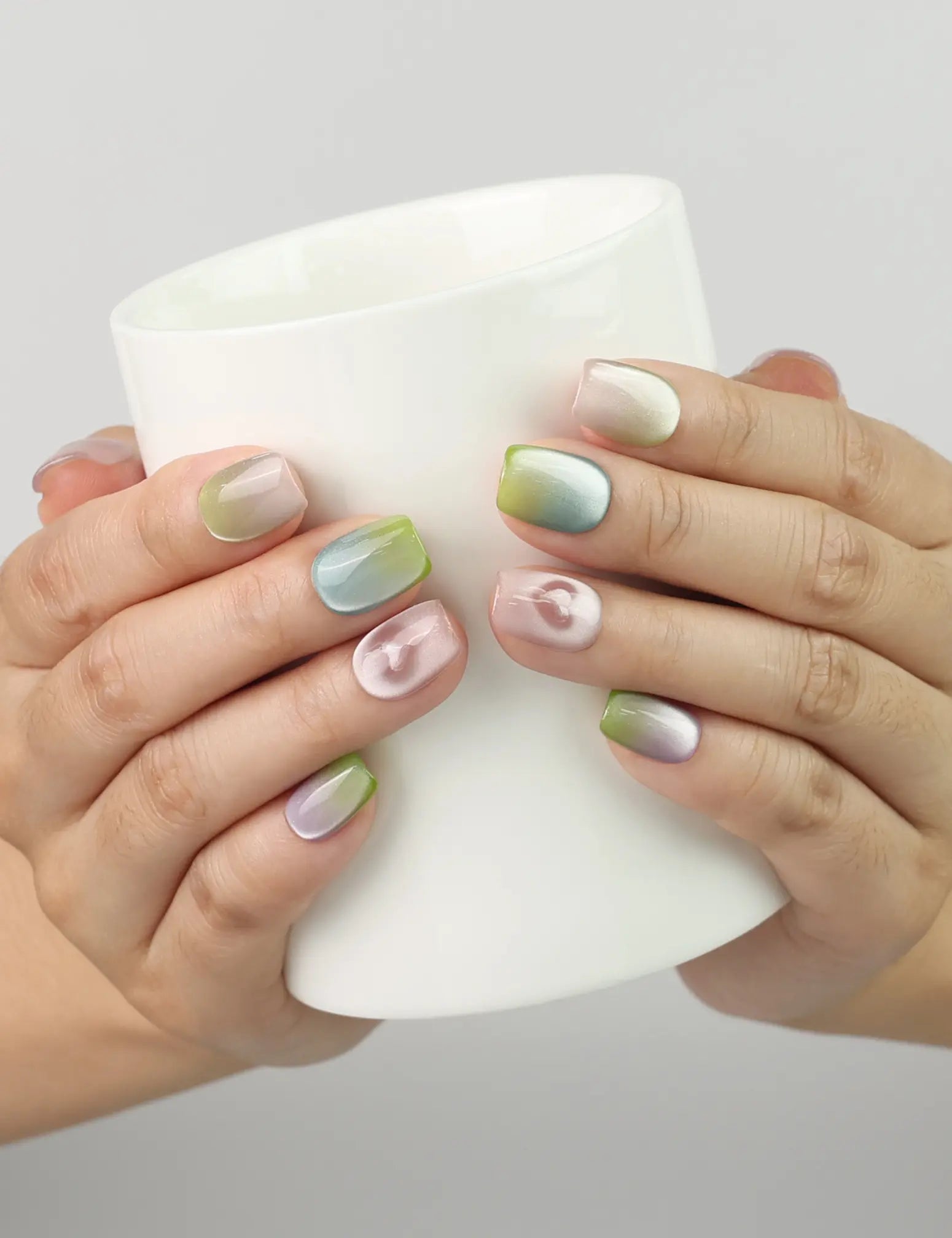 Hand holding a cup while wearing Gradient Heart handmade press on nails, sweet and coquette nail design