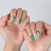 Side view of Naillover short almond press-on nails with fresh green foliage art and elegant metallic gold detailing